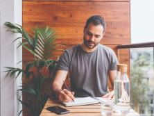 man sitting at patio table with pen and notebook